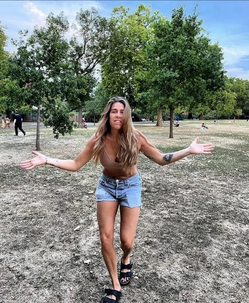 Louise Yerby smiling with her arms open in a London park